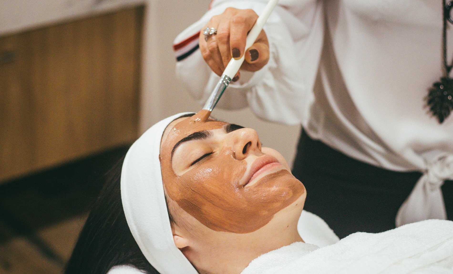 A client receiving a facial mask treatment at a spa